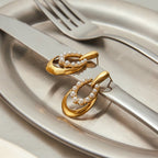 Gold earrings with pearls on a metallic surface