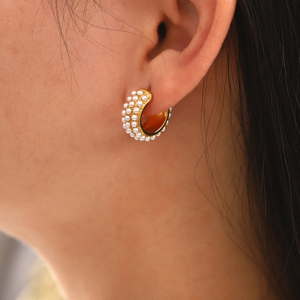 Close-up of an ear wearing a gold and pearl earring.