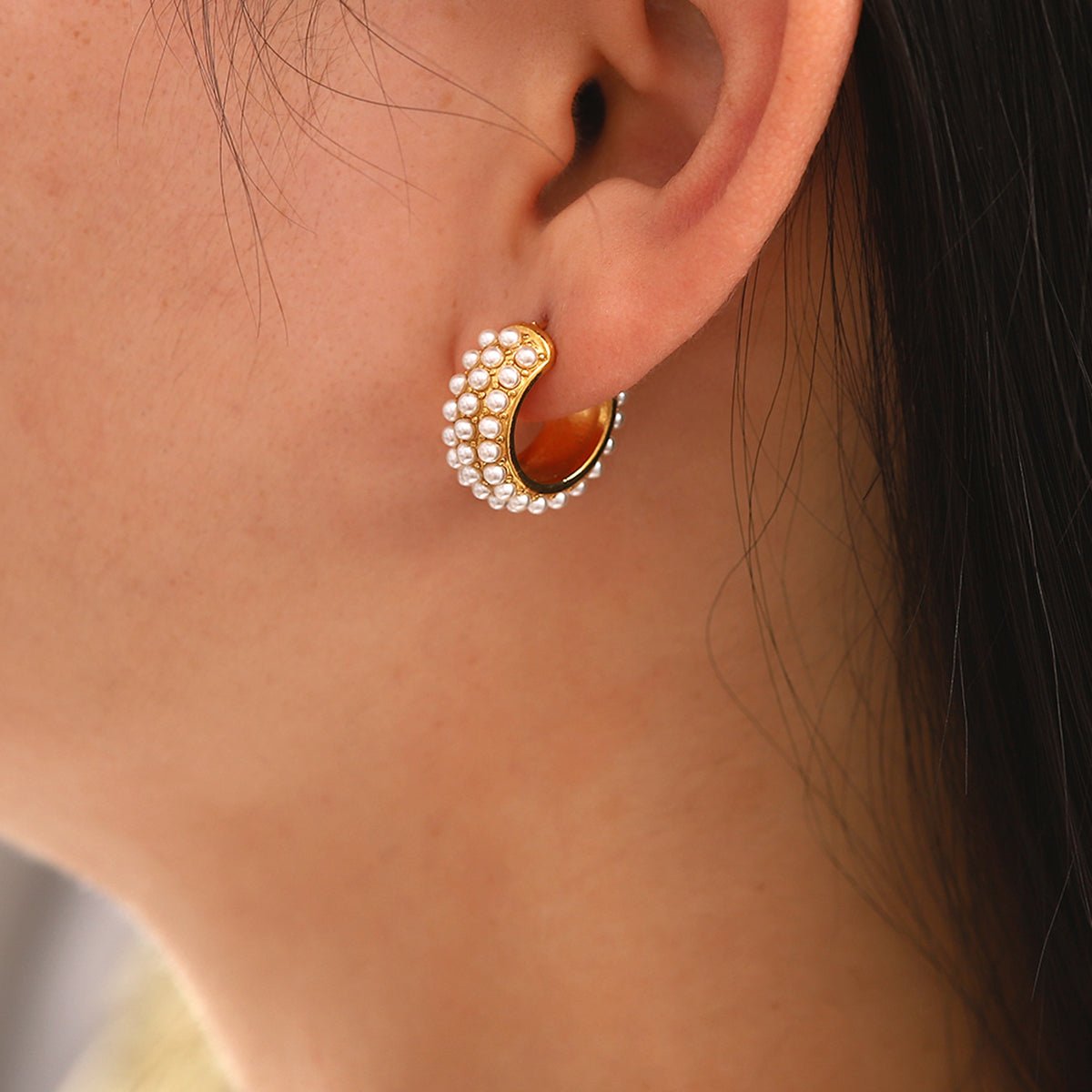 Close-up of an ear wearing a gold and pearl earring.