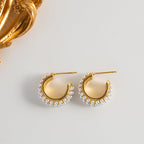 Gold hoop earrings with pearl accents on a light gray background