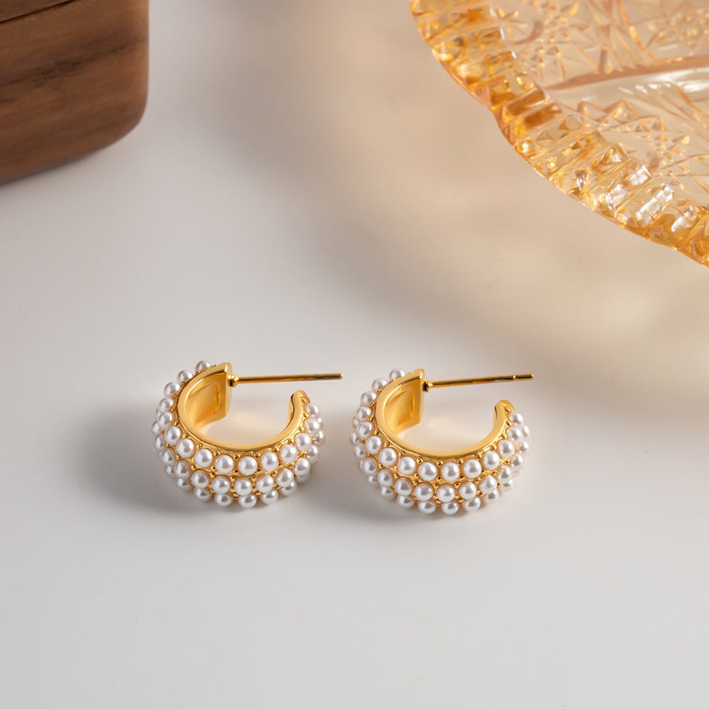 Gold hoop earrings with pearl accents on a light surface