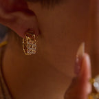 Close-up of a person wearing gold hoop earrings with small diamonds.