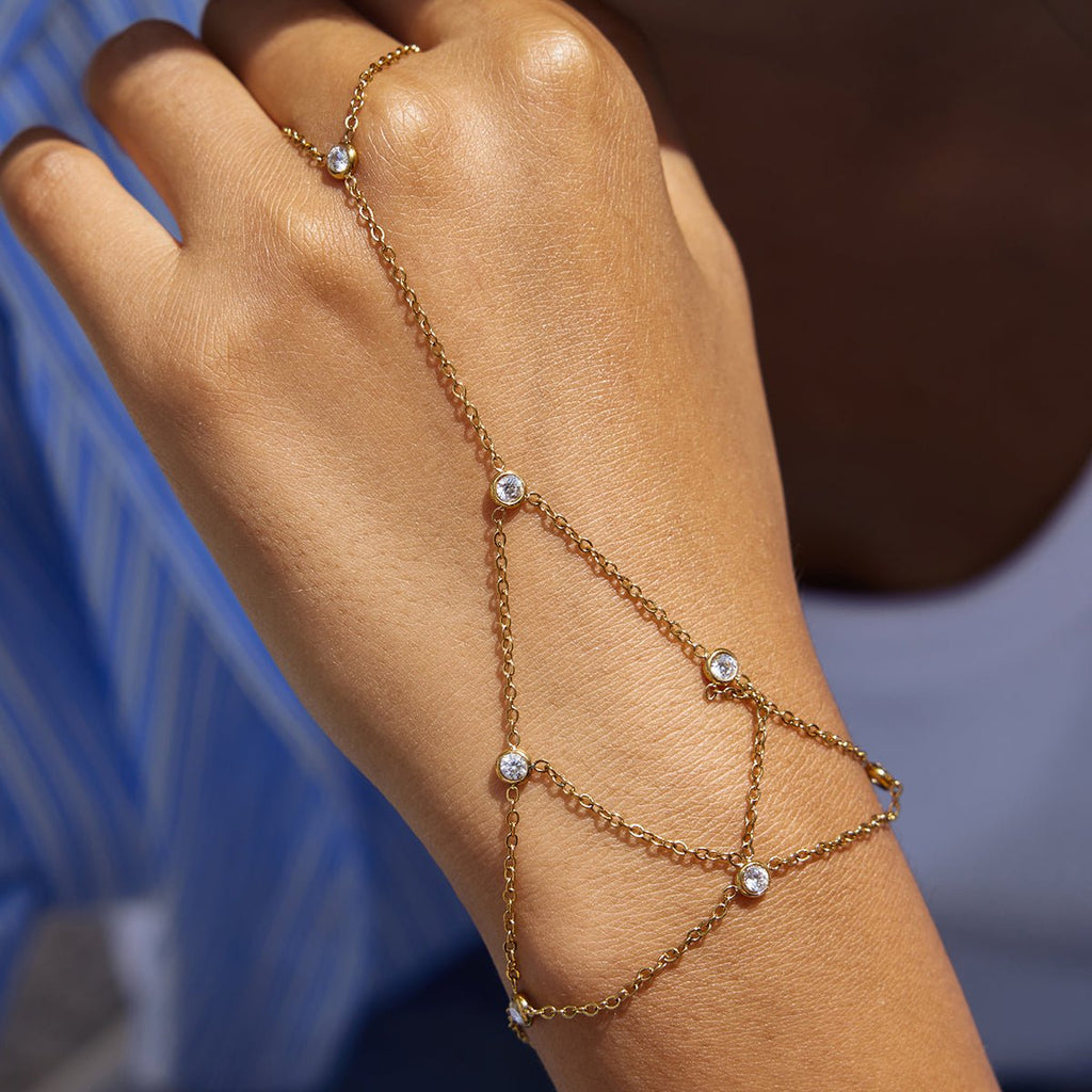 Gold chain bracelet with small diamonds on a wrist against a blurred background