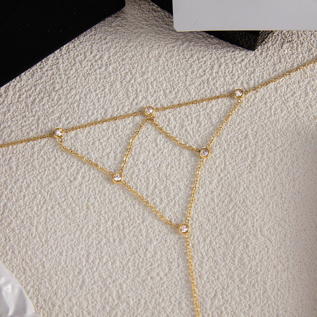 Gold chain bracelet with small beads on a textured beige surface