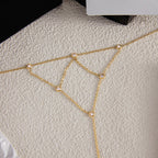 Gold chain bracelet with small beads on a textured beige surface