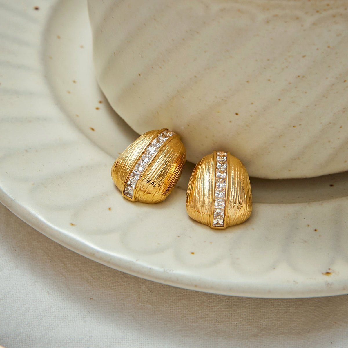 Gold earrings with diamond accents on a ceramic plate