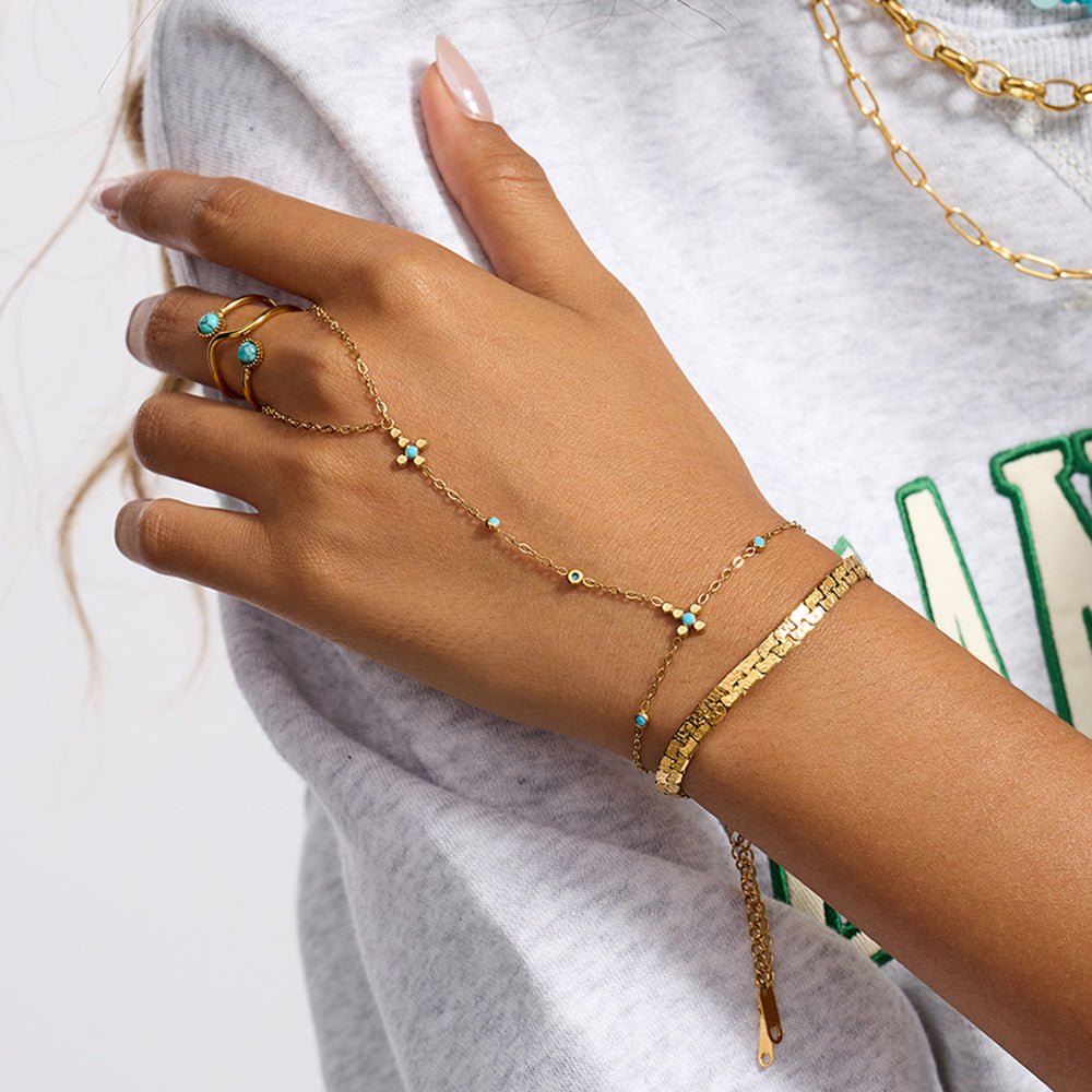 Hand wearing gold jewelry with turquoise stones on a white background