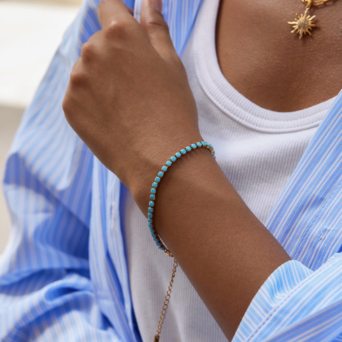 Person wearing a turquoise beaded bracelet on a blurred background