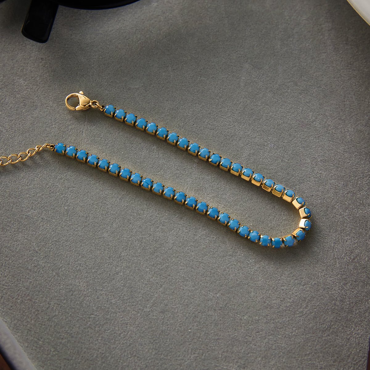 Gold bracelet with blue stones on a gray surface