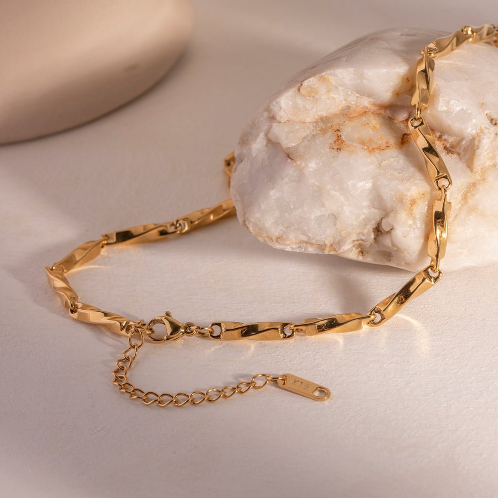 Gold bracelet on a textured surface with a neutral background