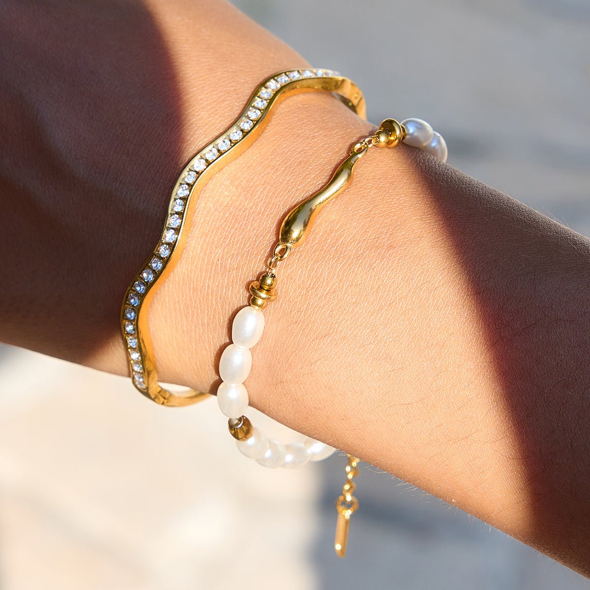 Gold and pearl bracelet on a wrist with a blurred background