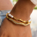 Gold bracelet with pearls and crystals on a wrist against a blurred background