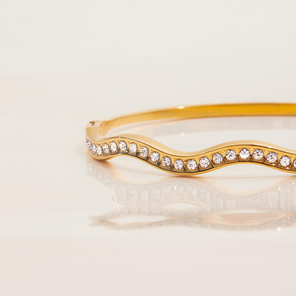 Gold bracelet with crystal embellishments on a light beige background