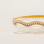 Gold bracelet with crystal embellishments on a light beige background