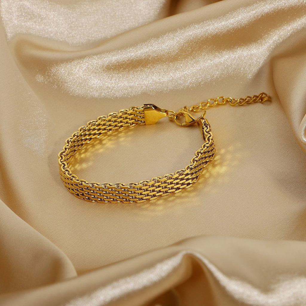 Gold bracelet on a beige satin background