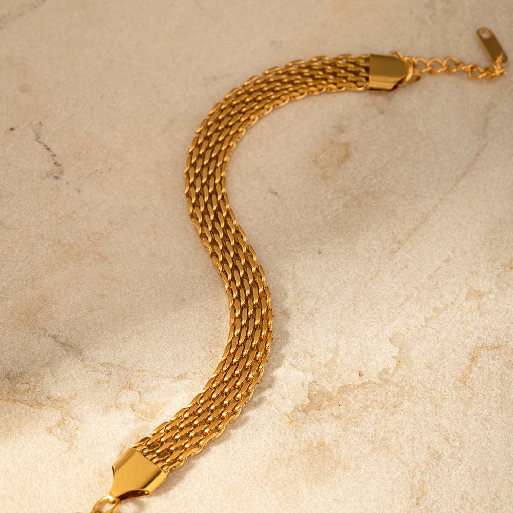 Gold chain bracelet on a beige marble surface