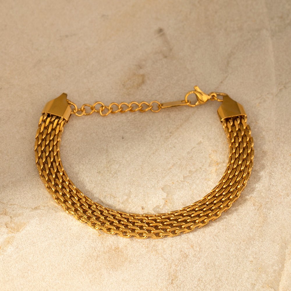Gold chain bracelet on a beige marble surface
