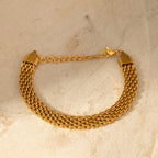 Gold chain bracelet on a beige marble surface