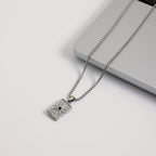 Silver necklace with a pendant on a light gray surface