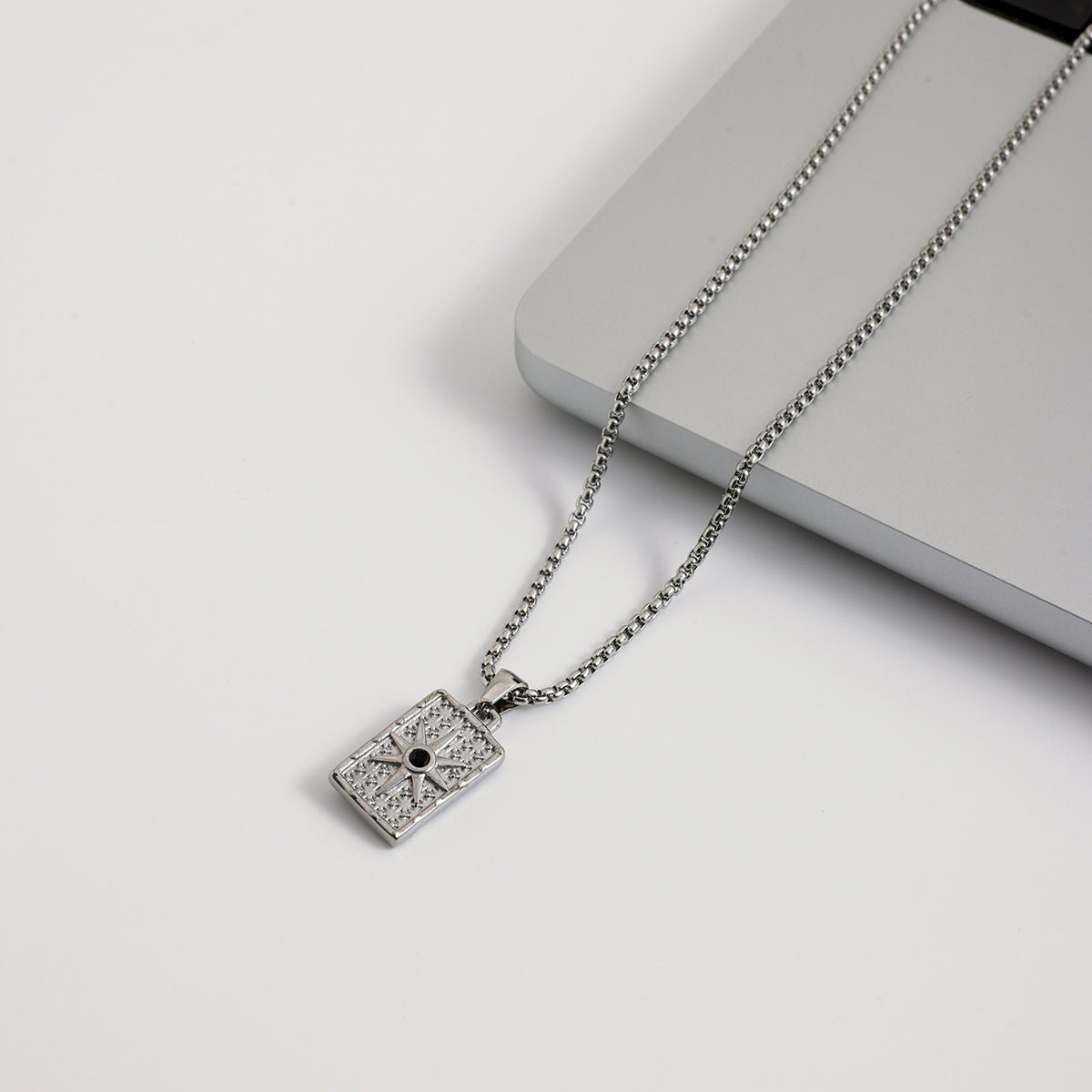 Silver necklace with a pendant on a light gray surface
