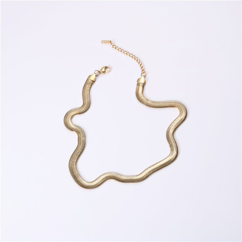 Gold snake chain necklace on a light gray background