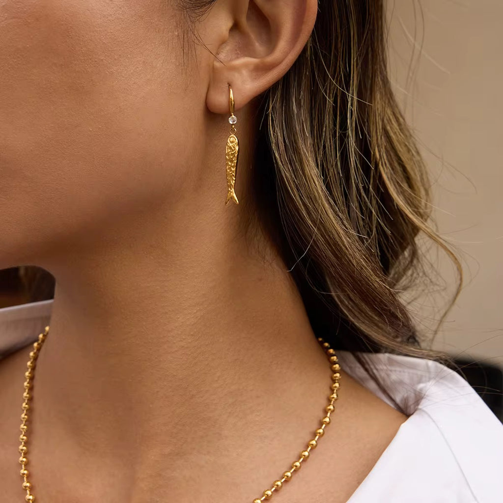 Front view of Very Fishy Indeed gold fish earrings on white background.