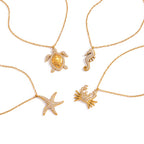 Gold necklaces with turtle, seahorse, starfish, and crab pendants on a white background