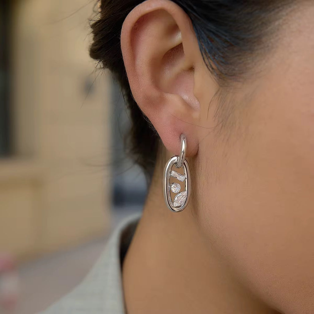 The Ritz Interlock drop earrings featuring 18k gold PVD plating and mixed crystal cuts.