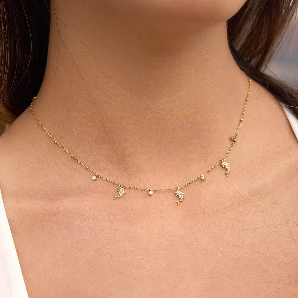 Dolphin Dance necklace featuring 18k gold PVD plating and pavé crystal dolphin charms.