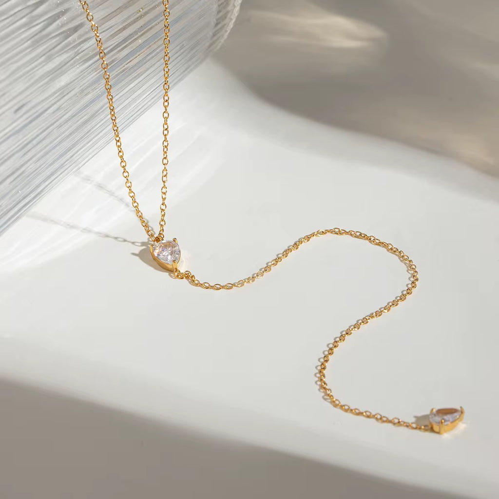 Gilded Tear lariat necklace featuring 18k gold PVD plating and dual teardrop crystals.