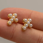Detail of the six luminous pearls set in a gold cross silhouette earring.