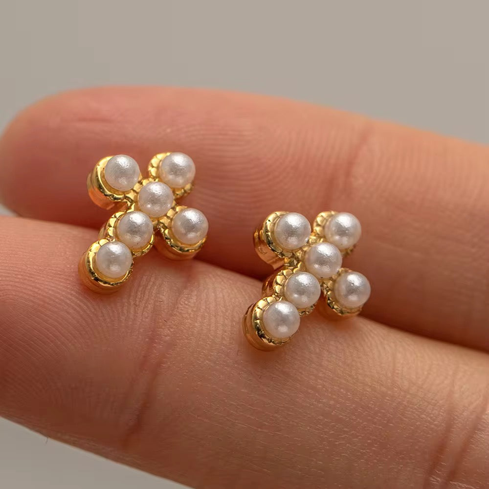Detail of the six luminous pearls set in a gold cross silhouette earring.