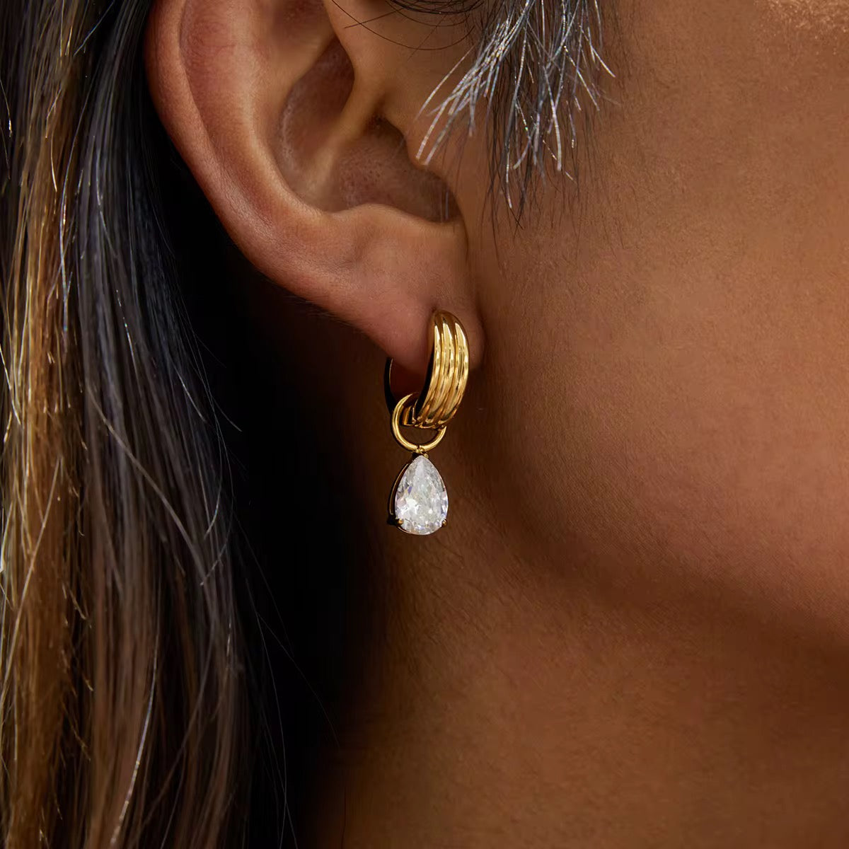 Gilded Teardrop huggie earrings with 18k gold PVD plating and oversized pear-cut crystals.