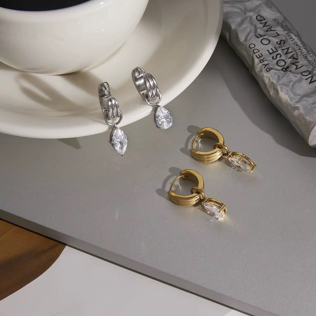 Detail of the secure prong setting and triple-ribbed gold hoop on a teardrop earring.