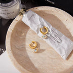 Guardian of the Blue Soul huggie earrings with turquoise evil eye charms and 18k gold PVD plating.
