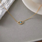 Detail of the delicate crystal-encrusted evil eye pendant on a gold link chain.