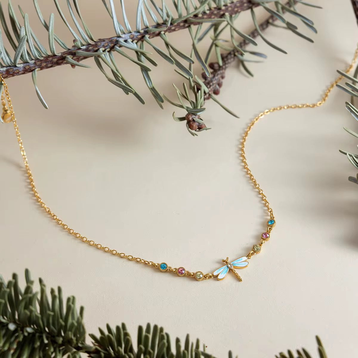 Waterproof Velvet Wings gold necklace with colorful turquoise and pink crystals.