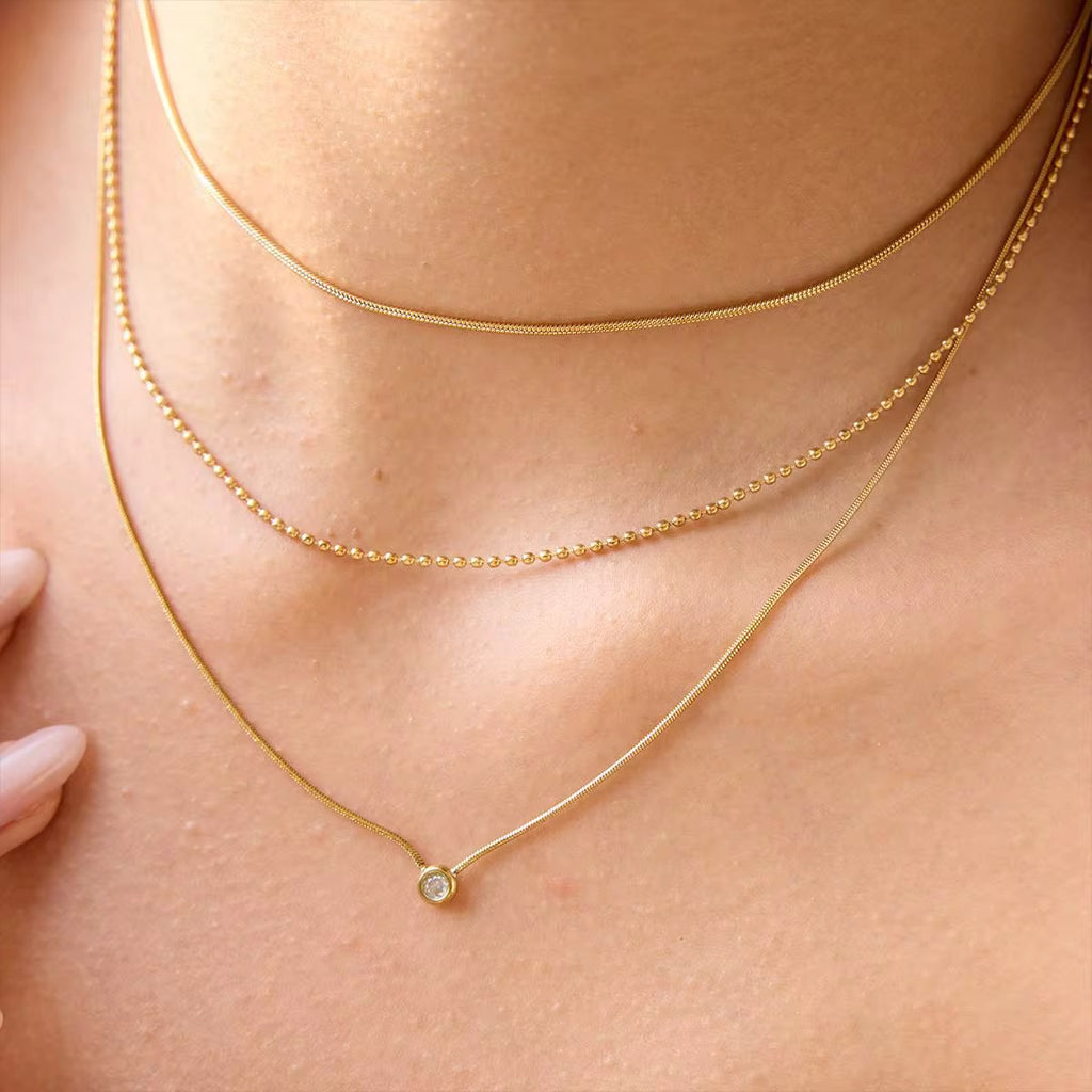 Waterproof gold triple chain necklace with bead and snake chain details for swimming.
