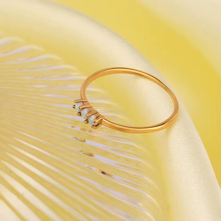 Waterproof gold stacking ring featuring three small round iridescent opal gemstones side by side.