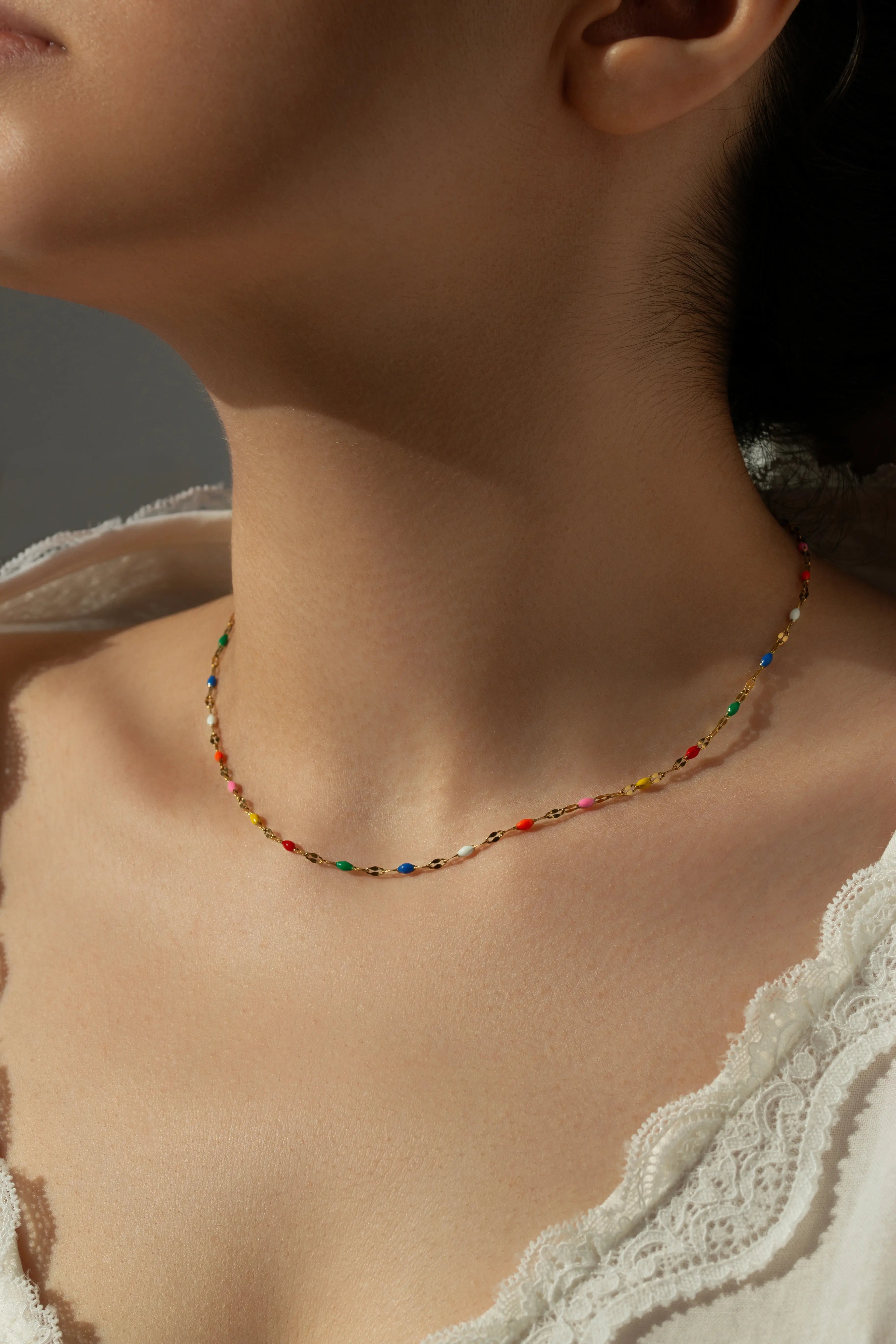 Waterproof gold choker necklace featuring colorful rainbow enamel beads arranged on a dainty lip chain.