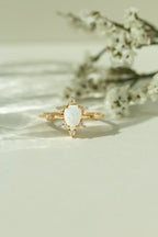 Unique natural teardrop opal engagement ring with a vintage inspired diamond cluster band. Alternative bridal jewelry and boho gemstone promise ring for women.
