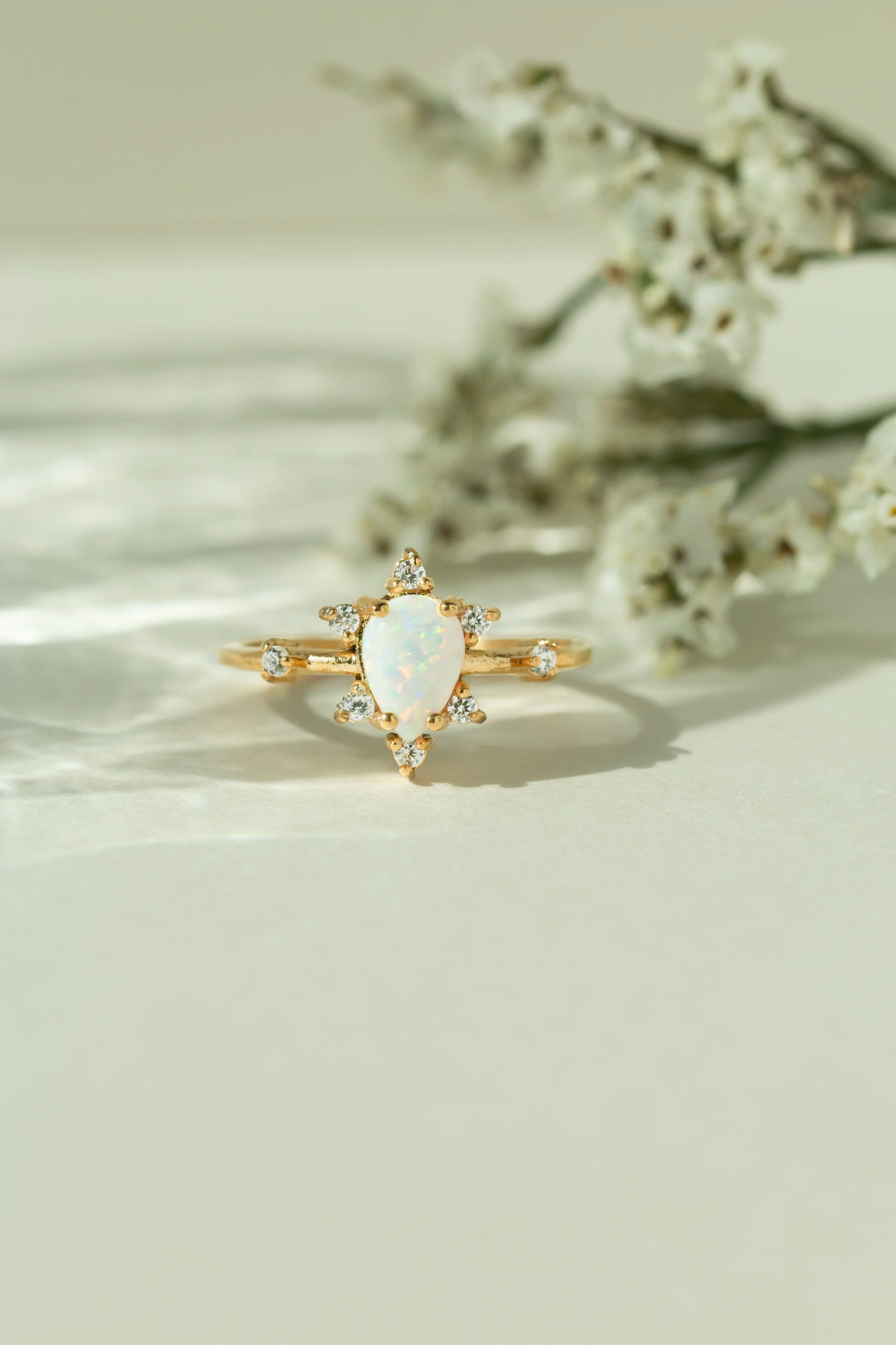 Unique natural teardrop opal engagement ring with a vintage inspired diamond cluster band. Alternative bridal jewelry and boho gemstone promise ring for women.
