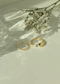 Minimalist 14k gold open pearl ring and chunky gold dome ring with a fresh water pearl accent. Elegant dainty seed pearl ring set styled next to white flowers under soft sunlight.