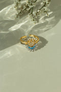Gold sun ring and silver crescent moon ring stacked together as a celestial set. Adjustable mixed metal sun and moon ring with clear and light blue crystal details on a sunlit backdrop.