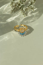 Gold sun ring and silver crescent moon ring stacked together as a celestial set. Adjustable mixed metal sun and moon ring with clear and light blue crystal details on a sunlit backdrop.