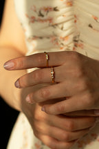  Gold natural opal ring with small side diamonds. Minimalist gemstone jewelry and dainty gold stacking ring styled with a white floral background.