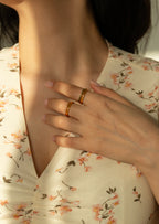 Minimalist yellow gold curved rings with pave clear and green crystals. Aesthetic matching dynamic stacker rings, fine bohemian style curved eternity bands styled with white flowers.