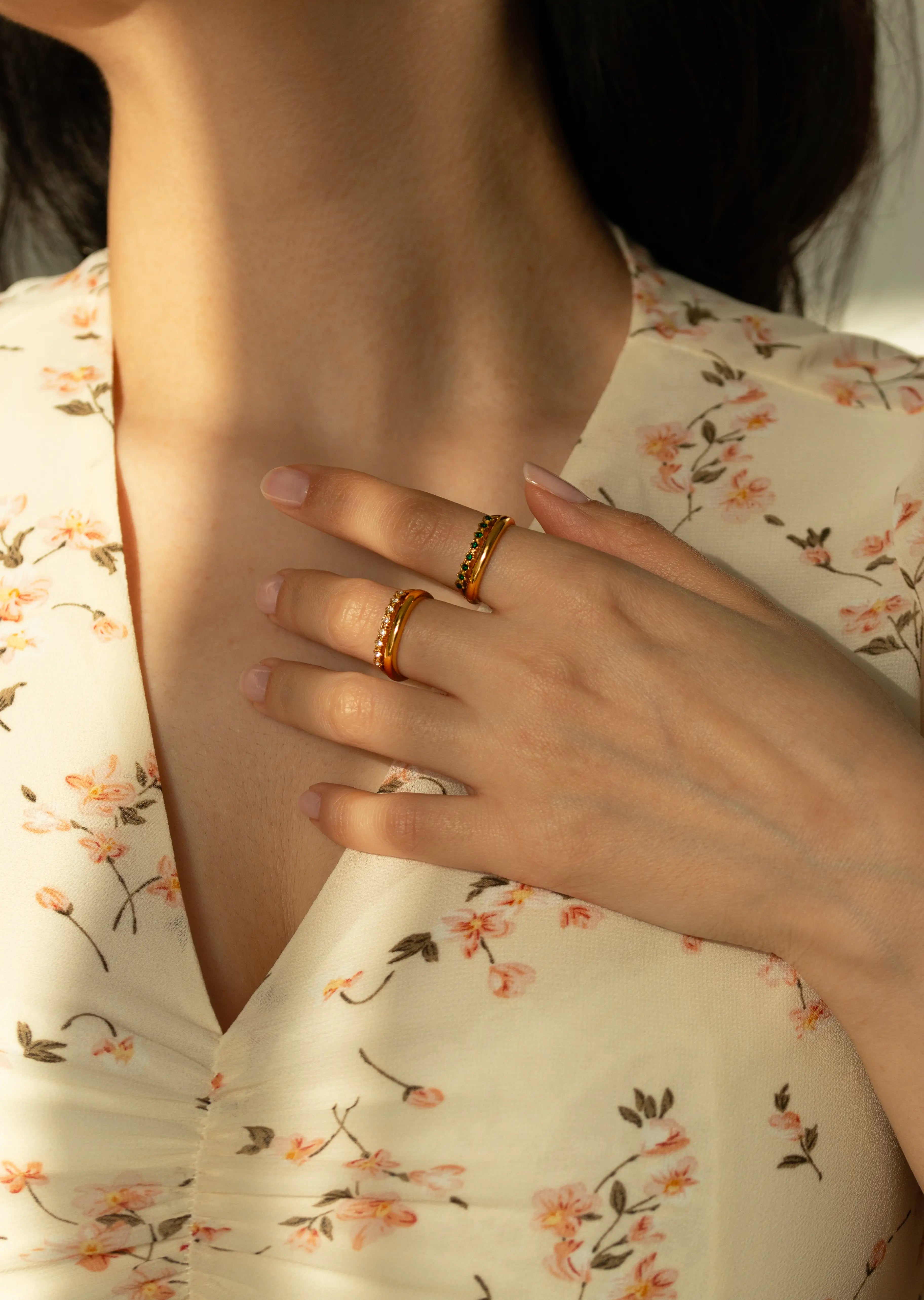 Minimalist yellow gold curved rings with pave clear and green crystals. Aesthetic matching dynamic stacker rings, fine bohemian style curved eternity bands styled with white flowers.