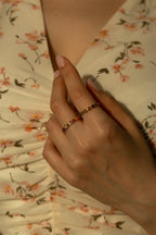  Dainty minimalist gold beaded ring featuring colorful bezel crystals including pink blue green and yellow gems. Aesthetic multi stone rainbow jewelry styled with white flowers.