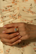 Trendy celestial sun and moon matching rings featuring blue topaz colored stones and pavé cz crystals. Aesthetic bohemian mixed metal stacking ring set styled with delicate white flowers.
